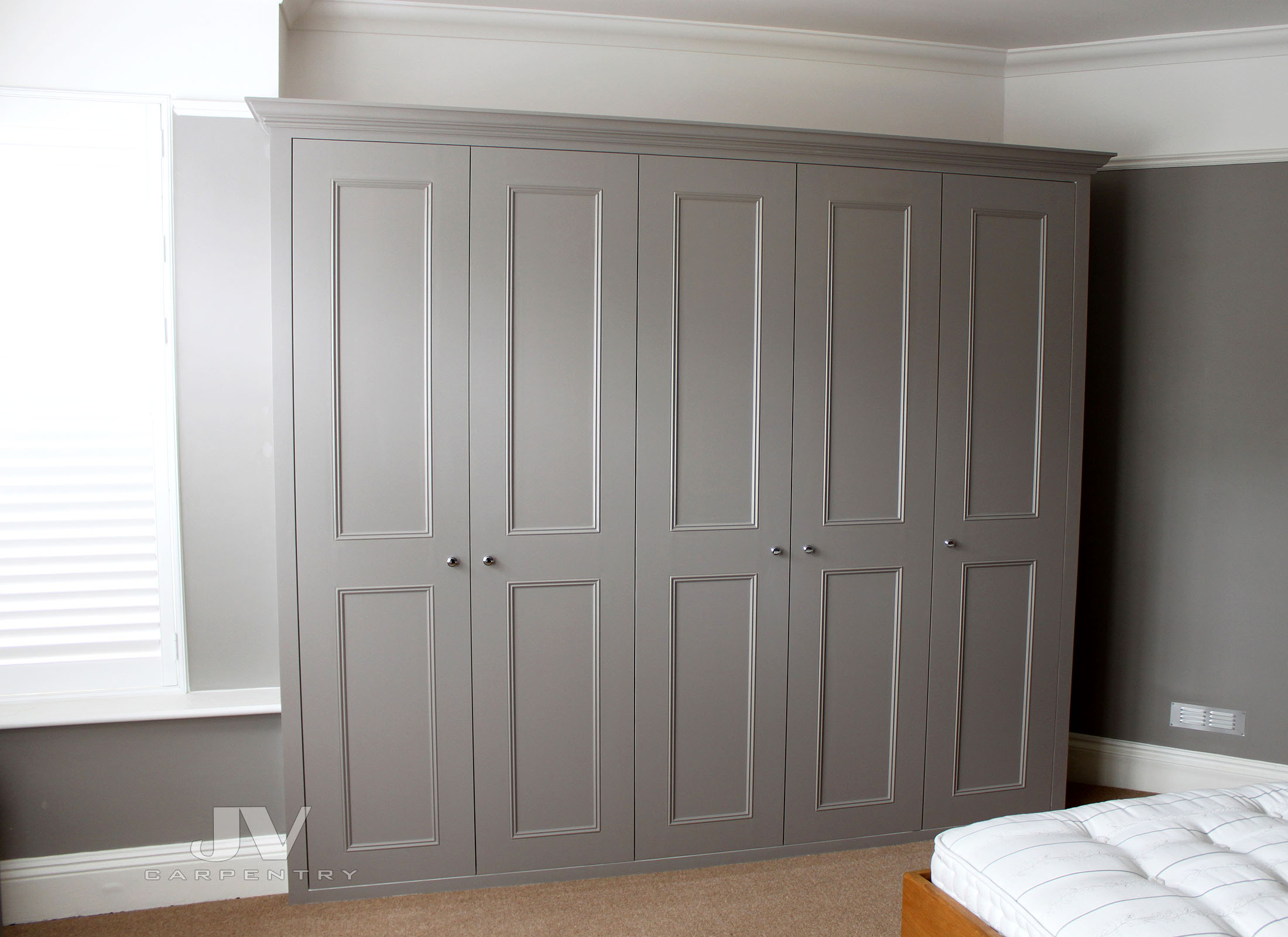 Grey fitted wardrobe with shaker beaded doors in a London bedroom